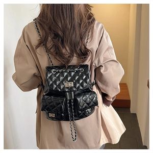 Detail showing the quilted faux leather texture and metal chain straps on the black backpack