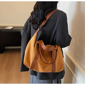 Detail of a large hobo tote bag in brown suede worn over the shoulder for a retro commute look