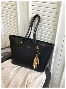 Detail of black PU leather tote bag with unique triple shoulder straps and beaded tassel charm