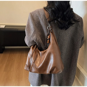 Brown vintage Hobo bag shown with wooden bead charm and fringe detail on the strap