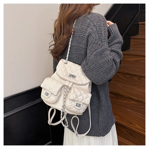 Close-up of white quilted backpack with chain straps and metallic turn-lock detail