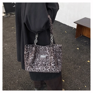 Detail of leopard print tote bag with silver chain strap and logo patch on thick canvas