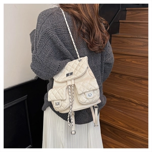 Rear view of cream quilted backpack with chain straps on a model in a casual setting