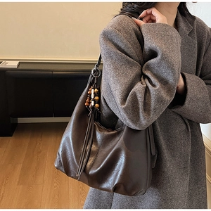 Detail of dark brown vintage shoulder bag with wooden bead tassel on a wool coat
