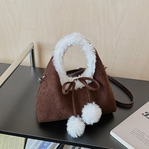 Détail d'un sac à main en daim marron foncé avec bordure en fourrure et nœud décoratif