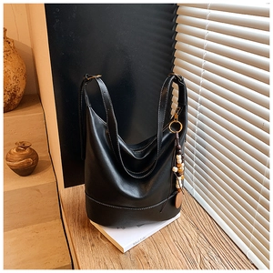 Detail of black large hobo bag with white stitching and rustic wooden bead charm