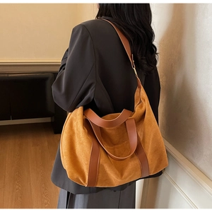 Detail of suede orange-brown tote bag featuring long brown leather handles on shoulder