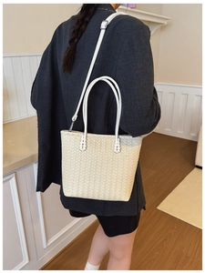 Gros plan détaillé d'un sac cabas tissé beige montrant la texture et la bandoulière
