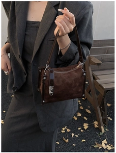 Detail of dark brown suede crossbody bag with quilted pattern and silver lock closure