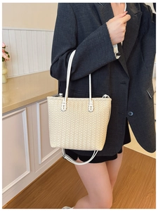 Gros plan sur le sac seau tressé crème montrant la texture et les poignées en cuir