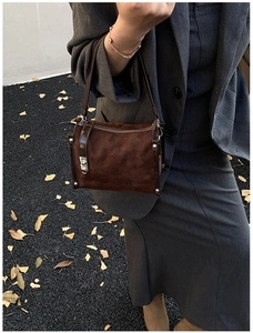 Close-up of brown suede crossbody bag with quilted patterns on a gray blazer