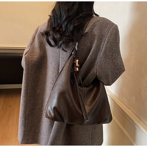 Macro detail of deep brown leather hobo bag with vintage bead decoration and soft texture