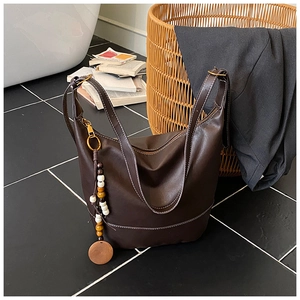 Detail view of dark brown leather tote with white stitching and bead tassel on books