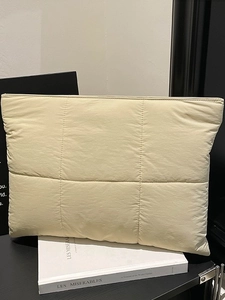 Quilted beige laptop sleeve bag with square stitching on a book for stylish daily use