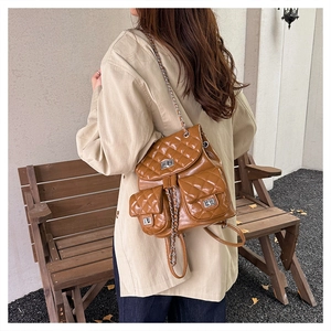 Detail view of the brown quilted leather backpack with silver clasp and chain straps