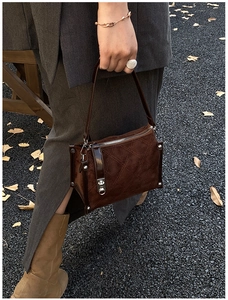 Detail of dark brown suede cylinder bag with classic quilted stitching and silver hardware