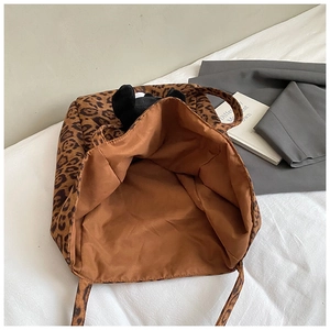 Detailed view of leopard print tote bag interior with dark lining and plush toy accessory