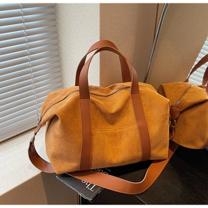 Detail of suede tote bag with leather handles and metallic zipper in a luxury setting