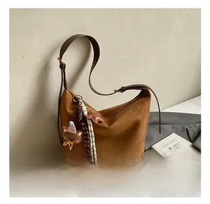 Brown suede bucket bag detail with star and tassel charms on leather shoulder strap