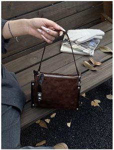 Close-up of deep brown suede handbag with silver zipper and metallic rivet details