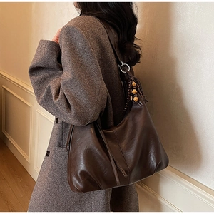 Close-up of a dark brown faux leather hobo bag with tassel and wood bead details