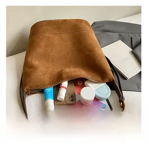 Macro view of interior storage capacity in brown faux suede bucket bag with various items