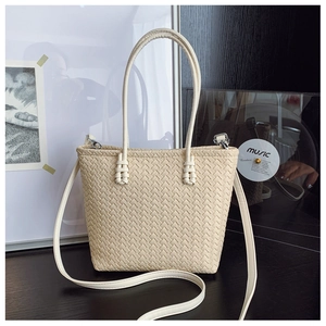 Détail du sac cabas tressé crème montrant la texture cuir et la boucle en métal argenté