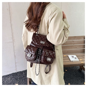 Detail view of coffee brown quilted backpack with silver chain straps and turn-lock closure