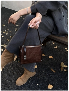 Close-up of diamond-stitched dark brown suede handbag with premium silver hardware detail