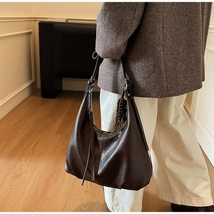 Close-up of vintage brown leather tote bag featuring a wooden bead tassel and soft PU texture