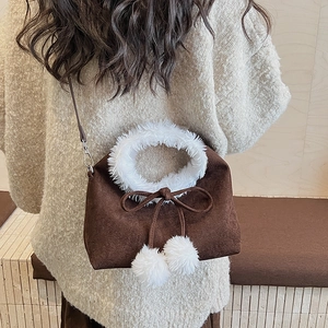 Détail du sac bandoulière en daim marron foncé avec bordure en fausse fourrure blanche et pompons