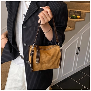 Detail of suede crossbody bag featuring quilted patterns and vintage metallic rivets