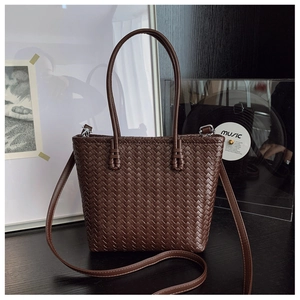 Détail d'un sac seau en cuir tressé marron foncé avec boucles en métal argenté