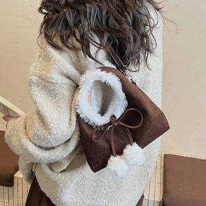 Détail du sac à main en daim avec poignées en peluche blanche et nœud décoratif à pompons