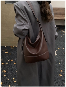 Detail of dark brown leather bucket bag featuring distinctive white contrast stitching
