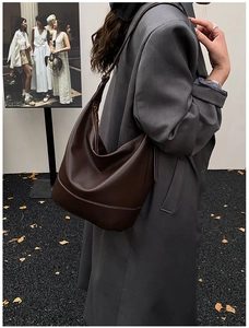 Detail of dark brown leather crescent bag with white contrast stitching and wide strap
