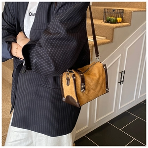 Detail of tan suede shoulder bag featuring quilted texture and silver lock buckle