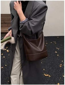 Detail view of coffee leather hobo bag featuring contrast white stitching and minimalist design