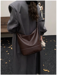 Close-up of a large dark brown hobo shoulder bag with contrast white stitching details