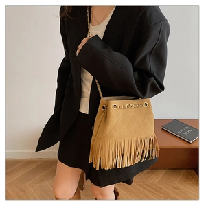 Detail of khaki bucket bag with quilted patterns, fringe trim, and gold chain strap