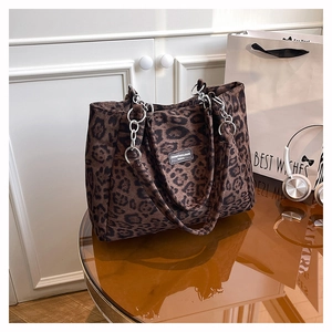 Detail of leopard print tote bag featuring a silver metal chain and brand logo tag
