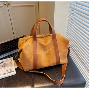 Detail of ginger suede tote bag featuring brown leather straps and smooth zipper closure