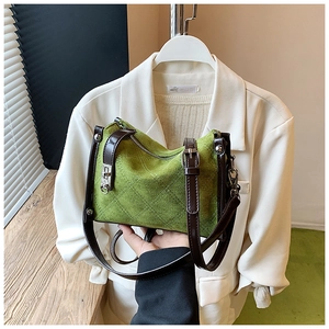 Detail of green quilted nylon bag featuring a silver twist lock and leather strap