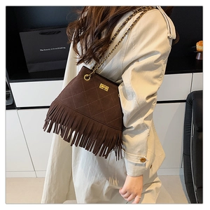 Detail of brown suede bucket bag with long fringe tassels and golden chain strap