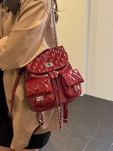 Quilted burgundy backpack with silver chain straps shown from a side-view on a model