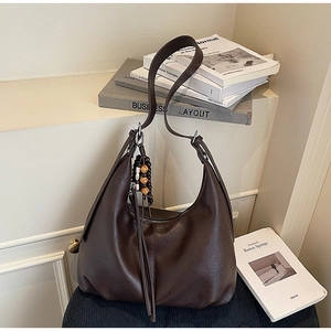 Detail of vintage dark brown hobo bag featuring a wooden bead tassel and smooth leather texture
