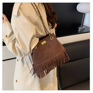 Detail of vintage brown suede bucket bag with fringe tassels and diamond quilting