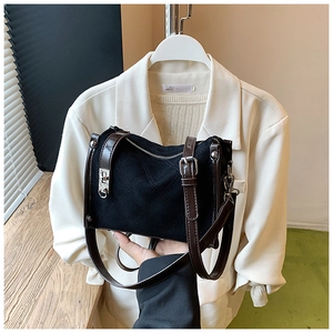 Detail of black quilted crossbody bag with silver buckle and brown leather strap