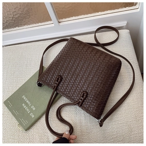 Vue détaillée de la texture tressée marron foncé et de la poignée nouée du sac seau