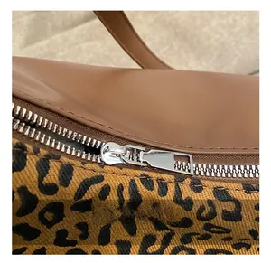 Détail de la fermeture éclair argentée sur le sac en toile léopard et cuir marron